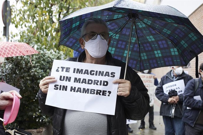 Archivo - Un hombre sostiene una pancarta donde se puede leer "¿Te imaginas un Madrid sin hambre?" 