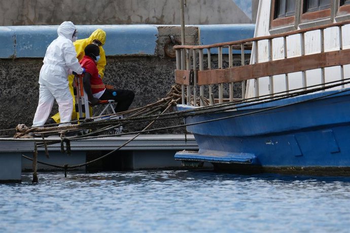 Dos personas protegidas ayudan a una persona en silla de ruedas a su llegada tras ser rescatada de una patera al sur de Fuerventura en abril