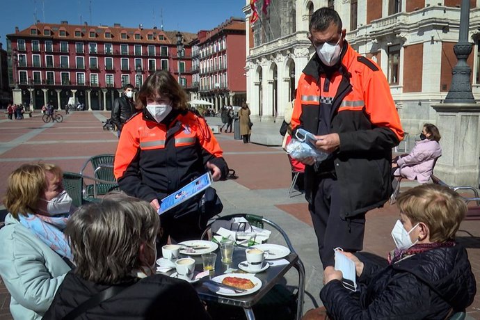 Voluntarios de Protección Civil informan sobre las medidas sanitarias a tres clientas de una terraza de Valladolid que cumplen correctamente la normativa.
