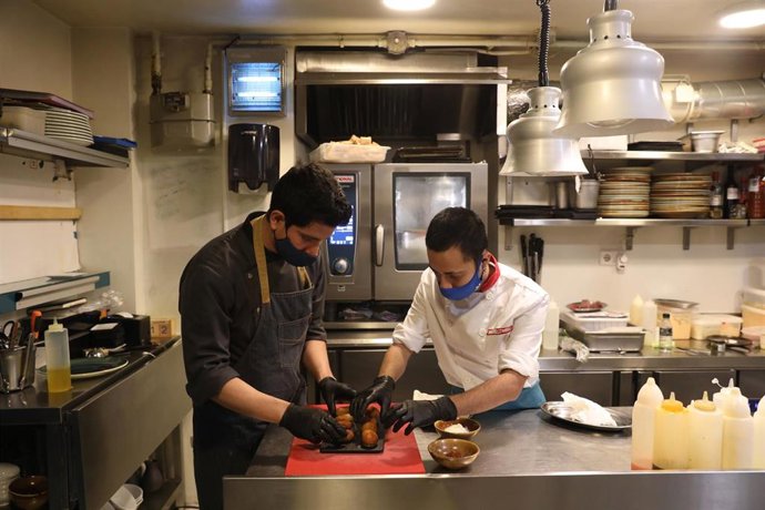 Archivo - Un camarero y un cocinero elaboran un plato en la cocina del Restaurante Marta, Cariño!, en Madrid (España), a 16 de octubre de 2020. 