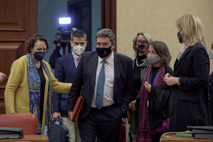 El ministro de Inclusión, Seguridad Social y Migraciones, José Luis Escrivá (centro), junto a la presidenta de la Comisión del Pacto de Toledo (i), Magdalena Valerio, se dirige a comparecer en una sesión de esta comisión en el Congreso