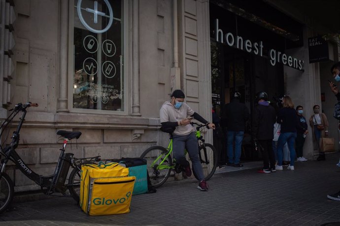 Archivo - Un trabajador de Deliveroo descansa en su bicicleta