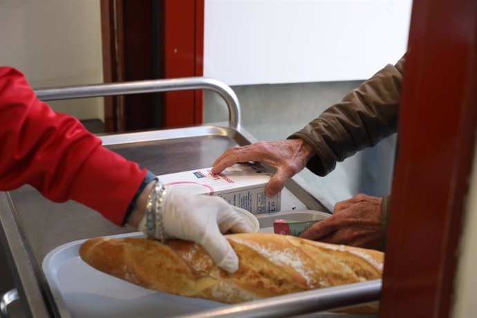 Archivo - Un voluntario trae comida a una persona como parte del reparto diario de alimentos de un comedor social, foto de recurso