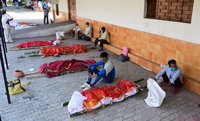 27 April 2021, India, Prayagraj: Family members wait with bodies of their relatives who died of Covid-19 to be cremated at an electric crematorium in Prayagraj. India hit record numbers of Covid-19 infections worldwide for the sixth day running on Tuesd