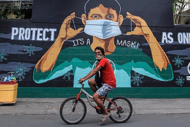 Un hombre cicula en bicicleta por una calle de Manila