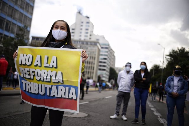 28 April 2021, Colombia, Bogota: A demonstrator wearing a face mask holds a placards says "No to tax reform" during a protest against a tax reform proposed by the government. Photo: Sergio Acero/colprensa/dpa