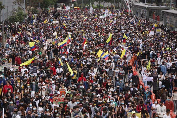 28 April 2021, Colombia, Bogota: People with face masks hold flags as they take part in a protest against a tax reform proposed by the government. Photo: Camila Diaz/colprensa/dpa