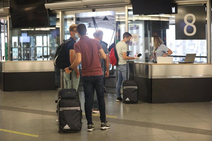 Archivo - Varios pasajeros con maletas muestran sus billetes para acceder al tren en la estación Madrid-Puerta de Atocha 