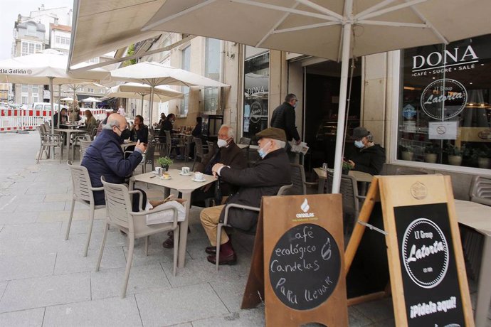 Varias personas en una terraza, el día en que entran en vigor nuevas medidas en la hostelería, en Vigo, Pontevedra, Galicia, (España).