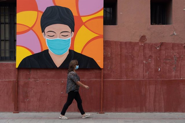 Una persona camina frente a un mural en homenaje a los trabajadores sanitarios durante la pandemia en Santiago, Chile.