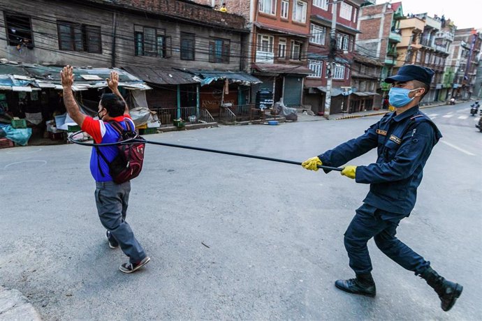 Archivo - Un policía nepalí detiene a un infractor de las medidas contra el coronavirus