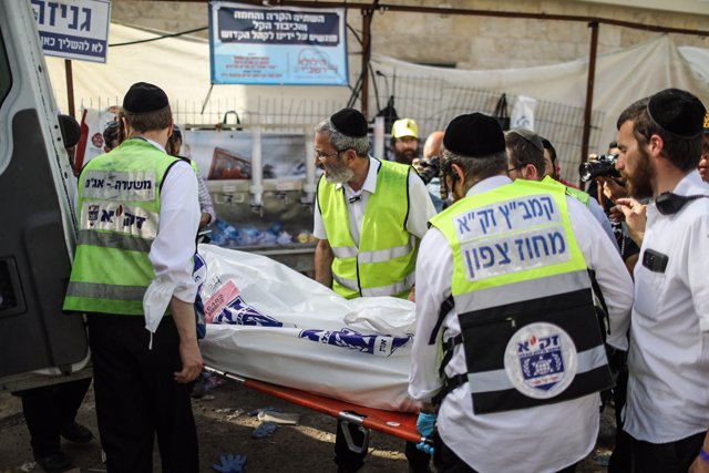 30 April 2021, Israel, Mount Meron: Israeli rescue workers carry a body of a victim into an ambulance, at the Jewish Orthodox pilgrimage site of Mount Meron.