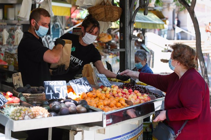 Archivo - Dos trabajadores de una frutería del Mercado Central de Valencia atienden a una clienta después de que el Ministerio de Sanidad autorizara a que la totalidad de la Comunidad Valenciana pasase en su conjunto a la fase 1 de la desescalada, en Va
