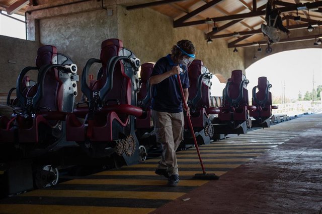 Archivo - Una trabajadora de PortAventura World protegida con mascarilla y pantalla mantiene las instalaciones durante la pandemia