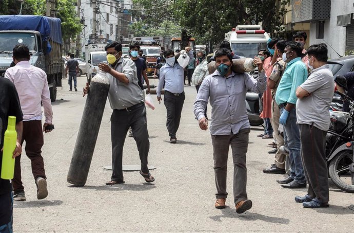 Un grupo de personas en Nueva Delhi acarrean con bombonas de oxígeno para sus familiares hospitalizados por coronavirus