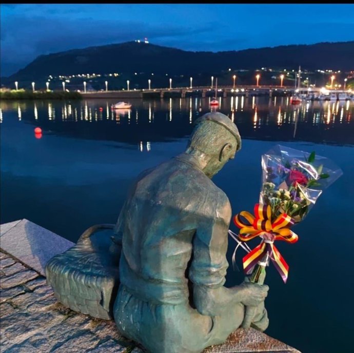 Estatua del pescador en el muelle e Astillero con flores por las víctimas en accidentes laborales