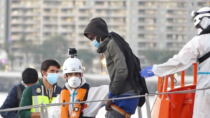 Archivo - Un miembro de la Cruz Roja ayuda a bajar del barco a un hombre migrante en el puerto de Arguineguín (Gran Canaria, España) a 17 de marzo de 2021. 79 inmigrantes de origen subsahariano que viajaban a bordo de dos pateras fueron trasladados esta