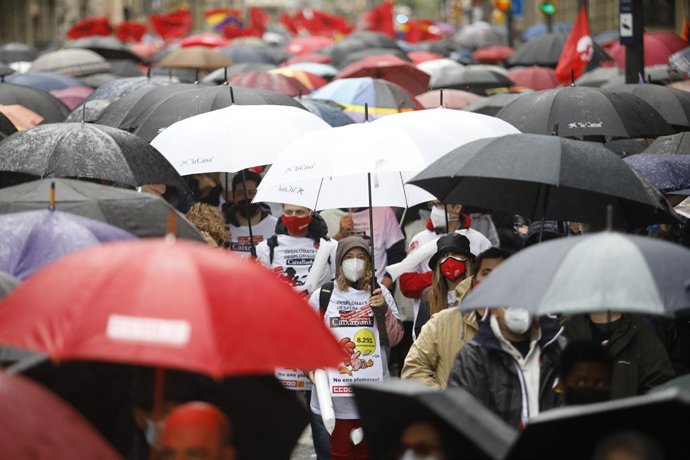 Manifestants amb mascarillas i paraigües en la concentració de Barcelona aquest 1 de Maig de 2021