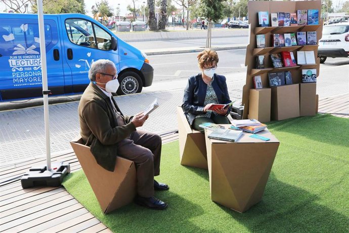 Dos personas mayores leen libros de la biblioteca móvil de la Diputación de Málaga que recorre los 87 municipios de menos de 20.000 habitantes.