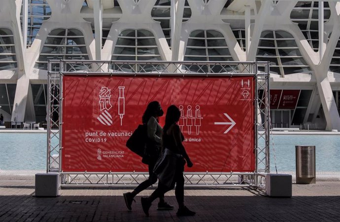Dos personas pasan por un cartel que indica el punto de vacunación de la Ciudad de las Artes y las Ciencias de Valncia