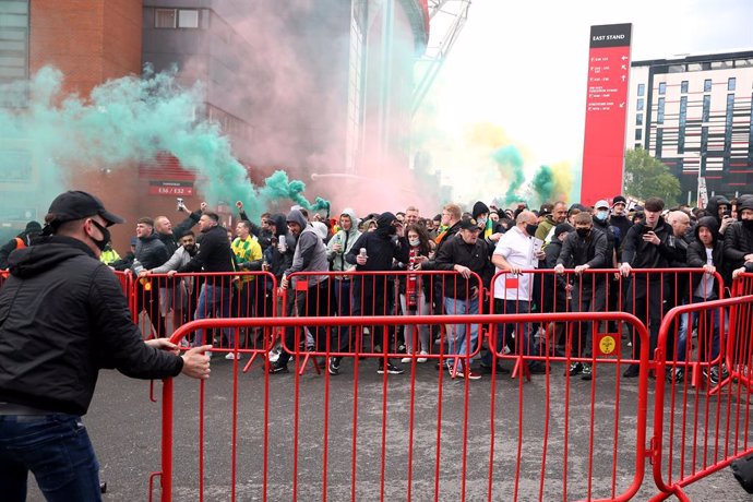 02 May 2021, United Kingdom, Manchester: Fans move barriers outside the ground as they let off flares whilst protesting against the Glazer family, owners of Manchester United, before their English Premier League soccer match against Liverpool at Old Tra