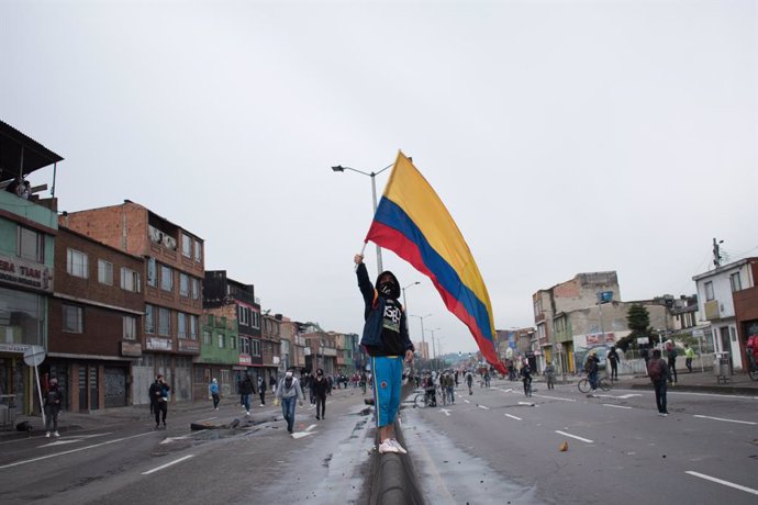 30 April 2021, Colombia, Bogota: A protester wave the Colombian flag during clashes with riot police at a protest against the tax reform bill proposed by the government. Photo: Daniel Santiago Romero Chaparro/LongVisual via ZUMA Wire/dpa