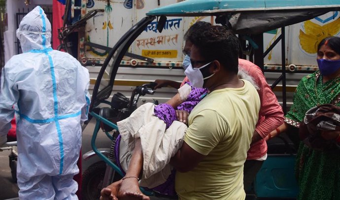 Un hombre lleva a un paciente de coronavirus en India.