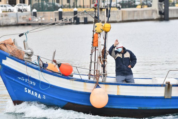 Un hombre saluda al mismo tiempo en que Agentes de Salvamento Marítimo de la Guardia Civil detienen a varios pesqueros marroquíes, a 22 de abril de 2021, en Ceuta, (España). La operación policial, que se produce por una presunta pesca de deriva realizad