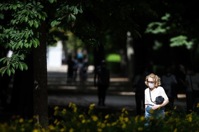Archivo - Una mujer protegida con mascarilla pasea por el Parque de El Retiro después de su reapertura tras haber sido cerrado por el Ayuntamiento de Madrid junto con otros parques históricos de la ciudad este domingo 31 de mayo al activarse la alerta roj