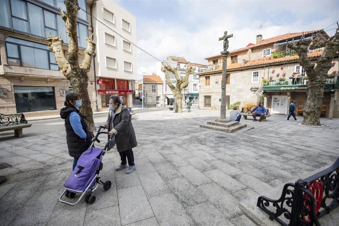 Dos mujeres conversan en una plaza de O Grove, el día en que entra en vigor el cierre perimetral del municipio, a 8 de abril de 2021, en O Grove, Pontevedra, Galicia, (España).  El Comité Clínico de la Xunta de Galicia ha decretado este martes el cierre