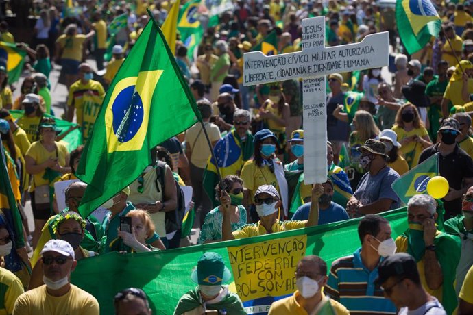01 May 2021, Brazil, Rio de Janeiro: Supporters of Brazilian President Jair Bolsonaro hold flags during a protest near Copacabana beach, to mark the May Day, International Worker' Day. Photo: Fernando Souza/dpa