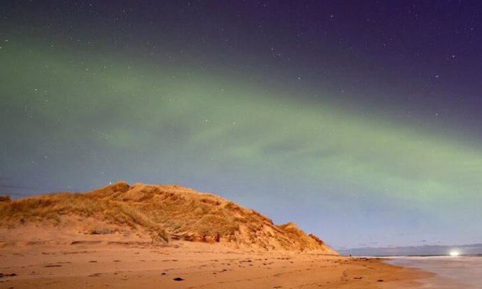 Un patrón de onda constante teñido de verde se puede ver en el evento de la aurora boreal similar a una duna.