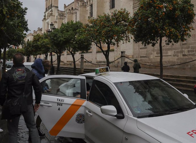 Archivo - Dos personas se montan en un taxi en el centro de Sevilla