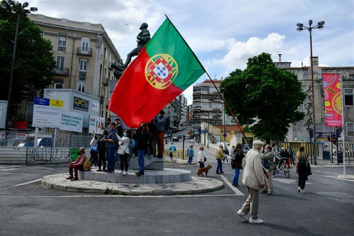 Un hombre camina portando la bandera de Portugal durante las marchas por el Día Mundial del Trabajo.