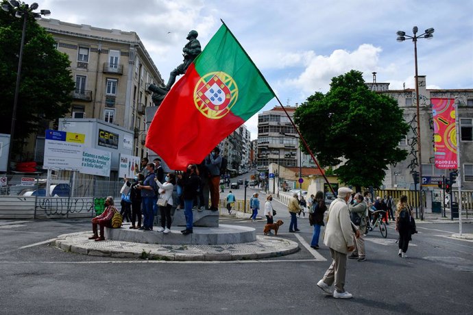 01 May 2021, Portugal, Lisbon: A man with a Portuguese flag marches near a monument in central Lisbon during a demonstration organized by the workers' unions, to mark the May Day, International Workers' Day. Photo: Jorge Castellanos/SOPA Images via ZUMA