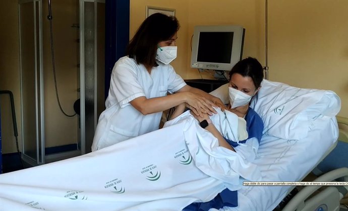 Una profesional sanitaria atiende a una madre que ha dado a luz y a su bebé recién nacido.