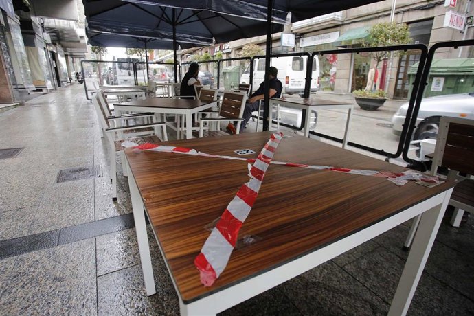 Una mesa de una terraza tachada con una cinta de prohibición en una calle de Vigo el día que entran en vigor las nuevas medidas para la hostelería.
