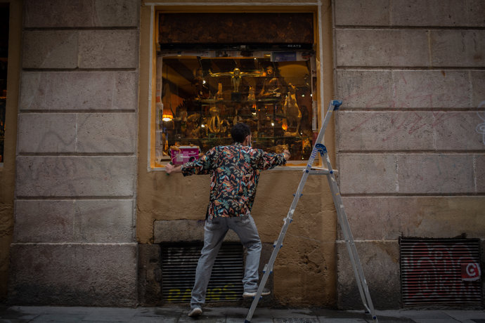 Un hombre pinta el escaparate de su tienda durante el tercer día de la entrada en vigor de las nuevas restricciones en Cataluña, en Barcelona, Cataluña (España) a 19 de octubre de 2020.  