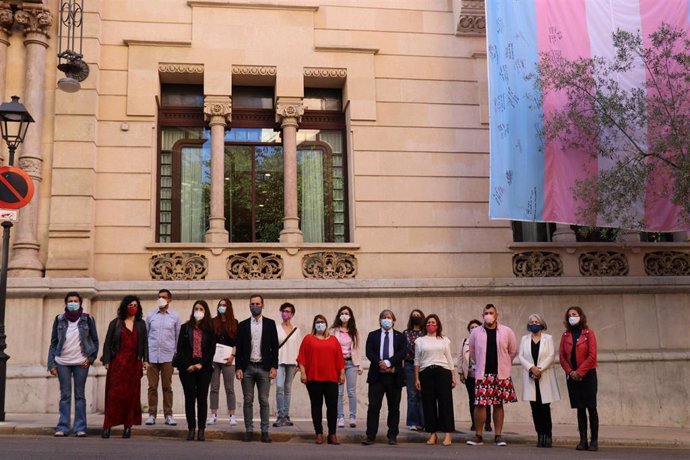 Representantes de diferentes instituciones de Baleares y de la entidad Ben Amics cuelgan la bandera trans en la sede del Parlament balear, en palma.