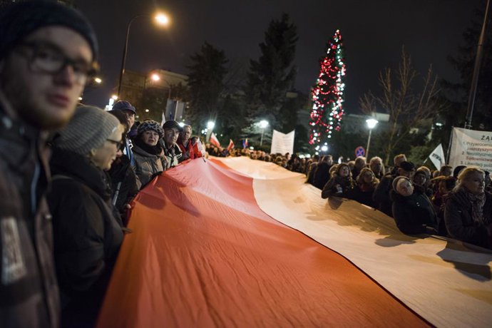 Archivo - 18 December 2019, Poland, Warsaw: People march with a large Polish flag during a demonstration against a draft amendment to the law on common courts and the Supreme Court which provides for the possibility of disciplining judges and dismissing