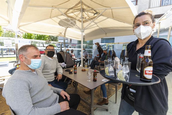 Una camarera sirve en una terraza del municipio de O Grove durante el primer fin de semana de apertura del cierre perimetral y la hostelería, a 2 de mayo de 2021, en Pontevedra, Galicia (España). O Grove abandonó el nivel máximo de restricciones el pasa