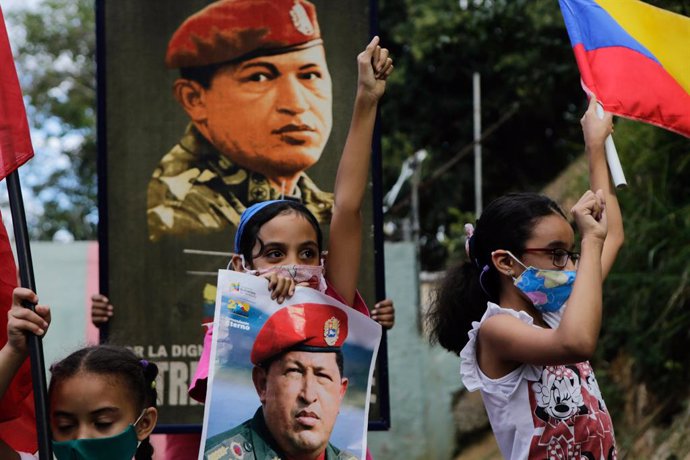 Archivo - 04 February 2021, Venezuela, Caracas: Children, along with a picture of the late President Hugo Chavez, take part in a march to commemorate the military uprising of 4 February 1992, in the 23 de Enero neighbourhood. Photo: Jesus Vargas/dpa