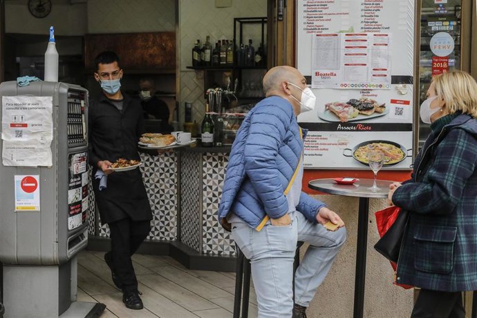 Archivo - Un camarero atiende a varios clientes en una terraza en Valncia