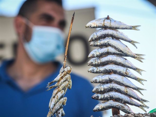 On the beach of Pedregalejo man prepares thickets of sardines with mask and safety measures due to the coronavirus crisis