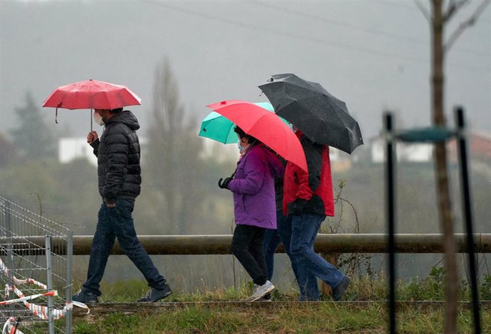 Archivo - Varias personas se refugian con un paraguas de la lluvia en Vitoria, País Vasco (España)