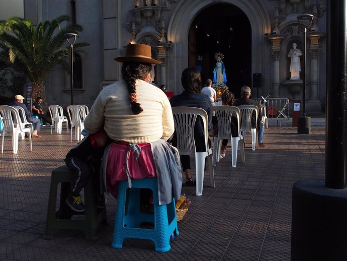 Una mujer en un acto religioso adaptado a las medidas contra la COVID-19 en Lima.