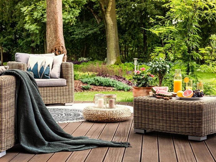 Close-up of rattan table with fruit and juice on it standing on a wooden patio in a spa facility garden