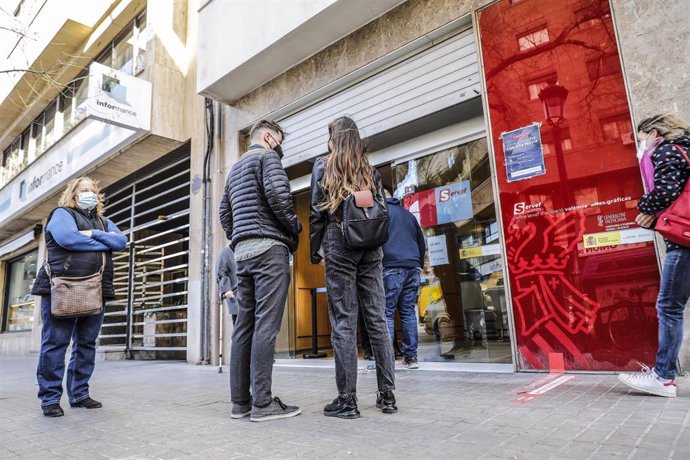 Archivo - Una pareja de jóvenes espera ser atendida en una oficina de empleo de Valencia