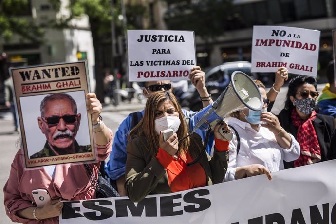 Una mujer con un megáfono, acompañada de varias personas con carteles, protestan contra el líder del Frente Polisario en la puerta de la Audiencia Nacional en Madrid