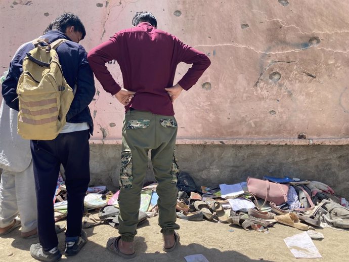 Dos personas inspeccionan el lugar del atentado contra una escuela femenina en la capital de Afganistán, Kabul